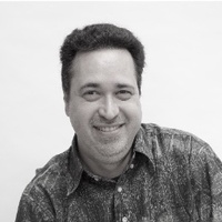 A black-and-white photo of a smiling man with dark hair