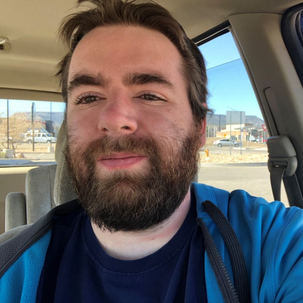 A smiling bearded white gentleman in a vehicle
