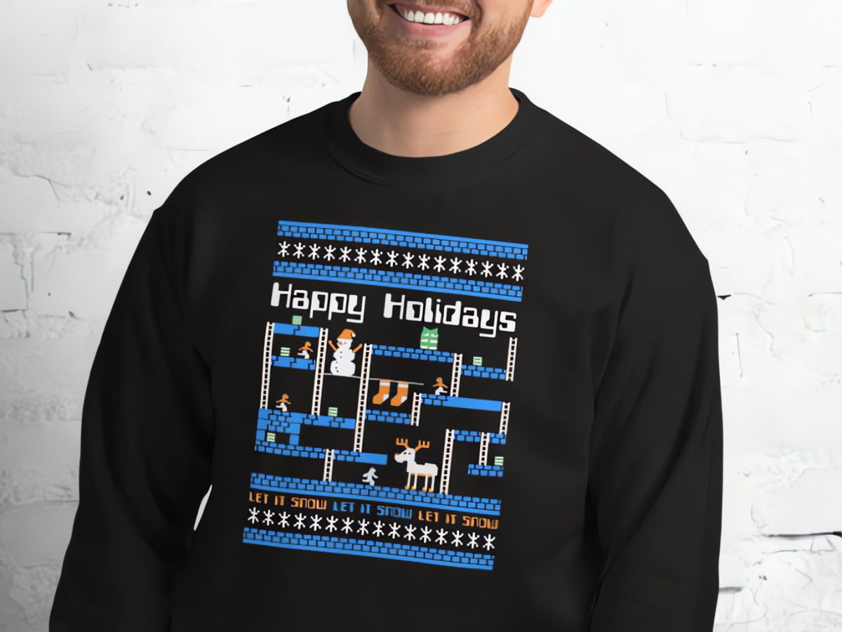 A screen from the computer game Lode Runner, printed on a black sweater being worn by a smiling white man