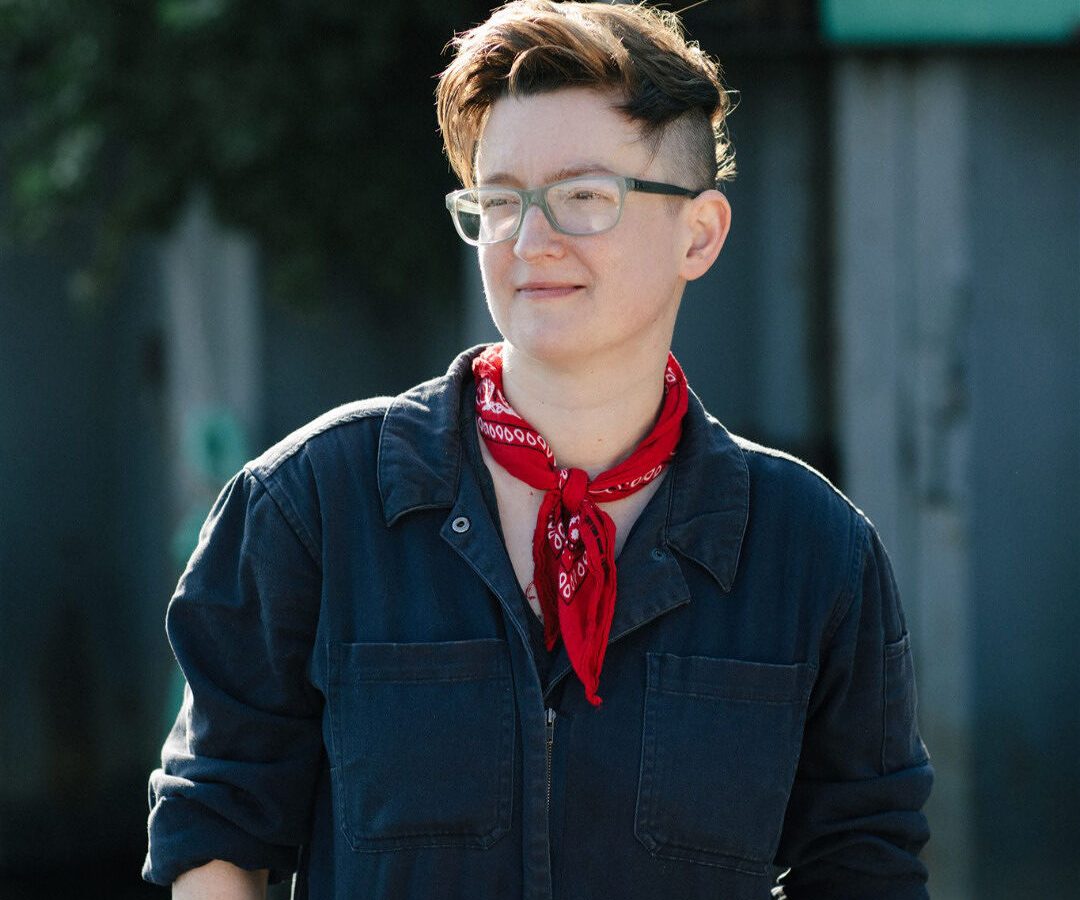 An individual with a sideshave, glasses, and red bandanna