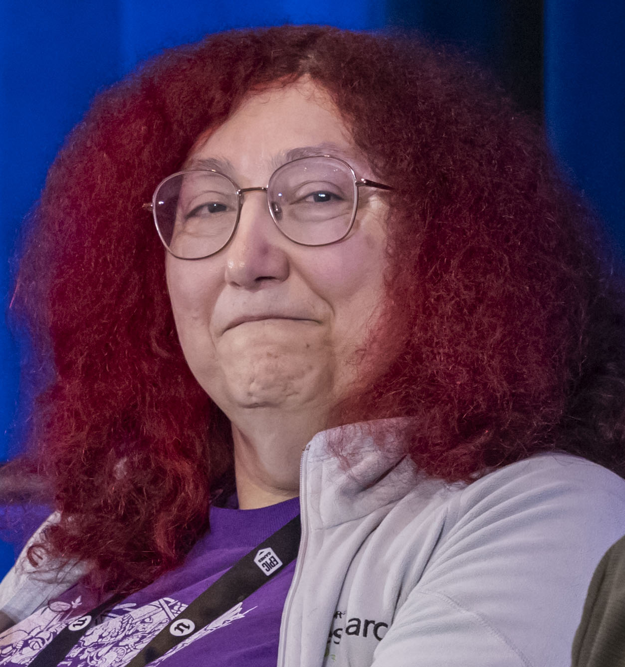 A smiling, red-haired white woman with glasses